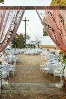 Υπεροχος στολισμος ξυλινης αψιδας για δεξιωση γαμου με υφασματα και λουλουδια