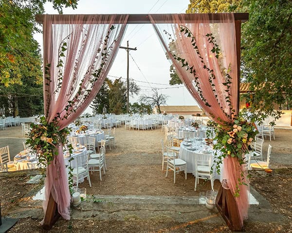 Υπεροχος στολισμος ξυλινης αψιδας για δεξιωση γαμου με υφασματα και λουλουδια