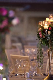 Στολισμός δεξίωσης με centerpieces από ψηλά κηροπήγια και λουλούδια