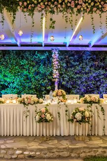 Εντυπωσιακός στολισμός τραπεζιού δεξίωσης γάμου με πλούσιες ανθοσυνθέσεις