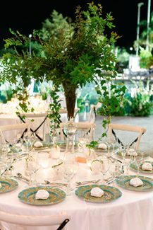 Πανέμορφος στολισμός τραπεζιών δεξίωσης γάμου με ψηλές συνθέσεις πρασινάδας