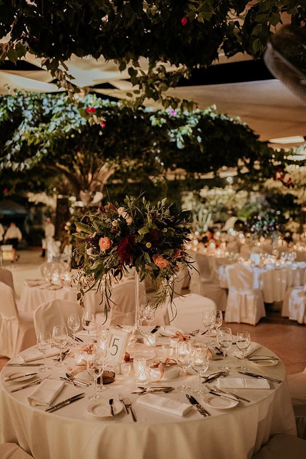 Εντυπωσιακός στολισμός τραπεζιού δεξίωσης με πλούσια πρασινάδα και τριαντάφυλλα σε coral αποχρώσεις