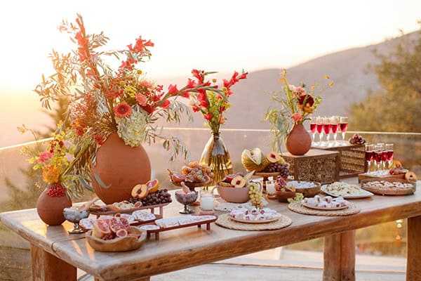 Ρουστίκ dessert table με διακόσμηση από κόκκινους γλαδίολους σε πήλινα βάζα