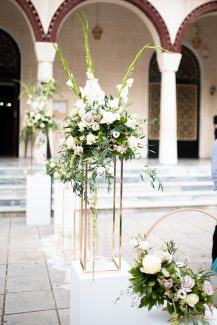 Elegant στολισμός εισόδου εκκλησίας με λευκές γλαδιόλες, τριαντάφυλλα, αμάρανθο, λυσίανθο και πλούσια πρασινάδα ευκαλύπτου