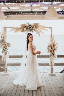 Ξύλινη αψίδα με φύλλα φοίνικα και ανάλαφρα pampas grass