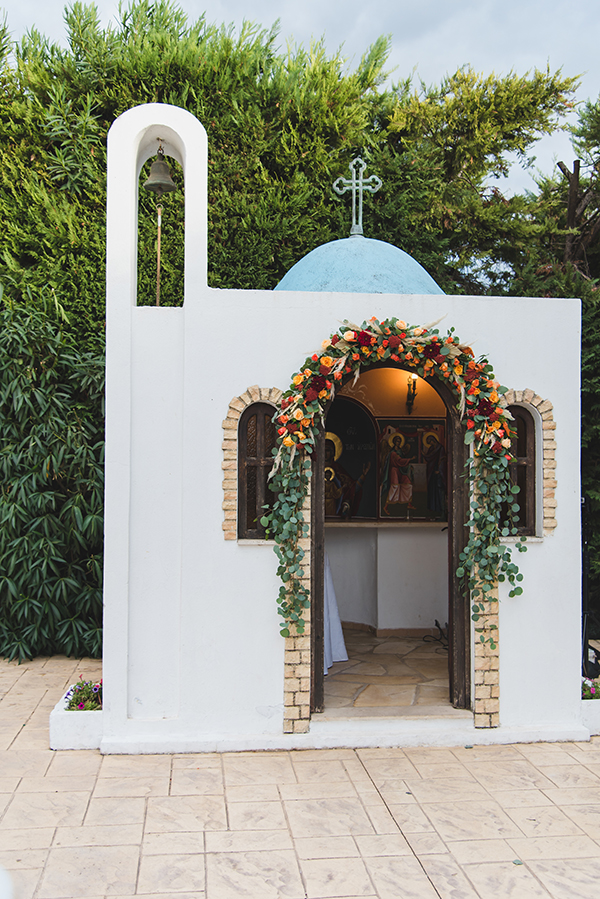 Μποέμ στολισμός εισόδου εκκλησίας από λουλουδένια γιρλάντα σε έντονους χρωματισμούς