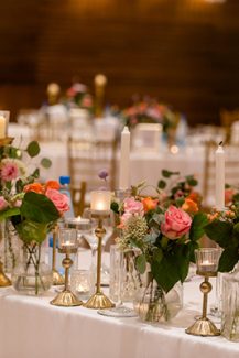 Στολισμός γαμήλιου τραπεζιού με χρυσά κηροπήγια και πολύχρωμα λουλούδια