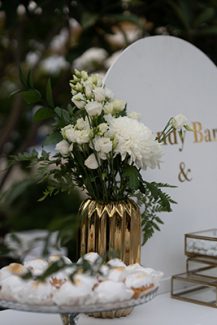 Elegant dessert table με λευκό backdrop και χρυσές βάσεις