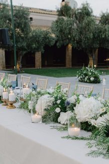 Ρομαντικός στολισμός γαμήλιου τραπεζιού με λευκά άνθη και μπλε πινελιές Ρομαντικός στολισμός γαμήλιου τραπεζιού με λευκά άνθη και μπλε πινελιές