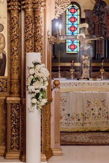 Λευκή λαμπάδας εκκλησίας με λευκό ανθοστόλισμό και πρασινάδα