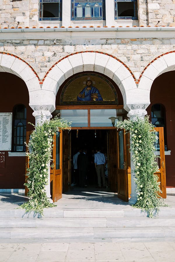 Λουλουδένια αψίδα με πλούσια φύλλα ελιάς και λευκά άνθη