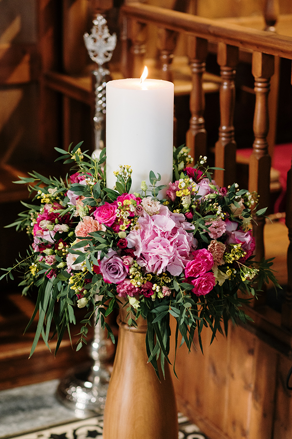 Στολισμός λαμπάδας με στεφάνακι από φούξια λουλούδια σε ξήλινη βάση