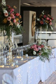 Στολισμός γαμήλιου τραπεζιού με ψηλά χρυσά stands και ανθοσυνθέσεις