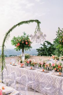 Luxurious στολισμός γαμήλιου τραπεζιού με πολυελαίους και πορτοκαλί ανθοσυνθέσεις