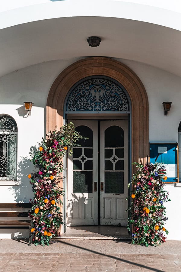 Εντυπωσιακή ασσύμετρη αψίδα στην είσοδο εκκλησίας από λουλούδια σε ζωηρά χρώματα