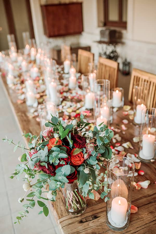 Ξεχωριστός στολισμός γαμήλιου τραπεζιού με αμέτρητα κεριά και ροδοπέταλα
