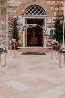 Ξεχωριστός στολισμός εισόδου εκκλησίας με χρυσά stands και λουλούδια