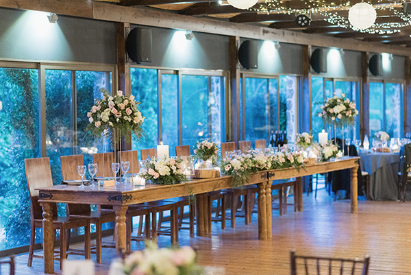 Ρουστίκ στολισμός γαμήλιου τραπεζιού με ψηλά stands, ξύλινες βάσεις και κεριά