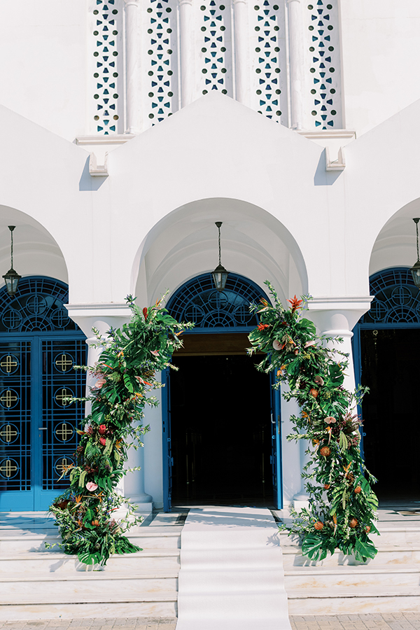 Πλούσιος στολισμός εισόδου εκκλησίας με τροπικά άνθη και πρασινάδες