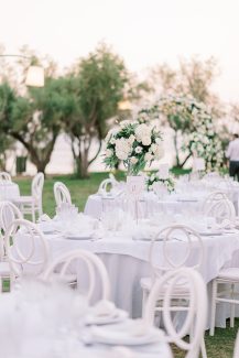 Ολόλευκος στολισμός τραπεζιών δεξίωσης με ψηλά centerpieces από ρομαντικά λουλούδια