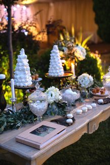 Διακόσμηση dessert table με γιρλάντα από φύλλα ελιάς και λευκά άνθη Διακόσμηση dessert table με γιρλάντα από φύλλα ελιάς και λευκά άνθη