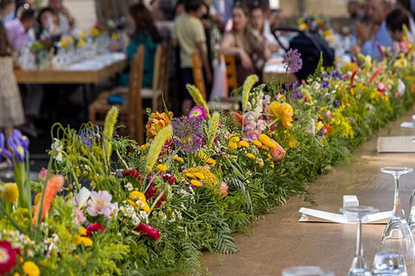 Ρουστίκ στολισμός γαμήλιου τραπεζιού με πλούσια γιρλάντα από λουλούδια του αγρού
