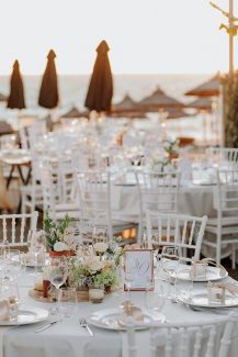 Υπέροχος στολισμός τραπεζιών δεξίωσης με χαμηλά centerpieces με ιβουάρ τριαντάφυλλα