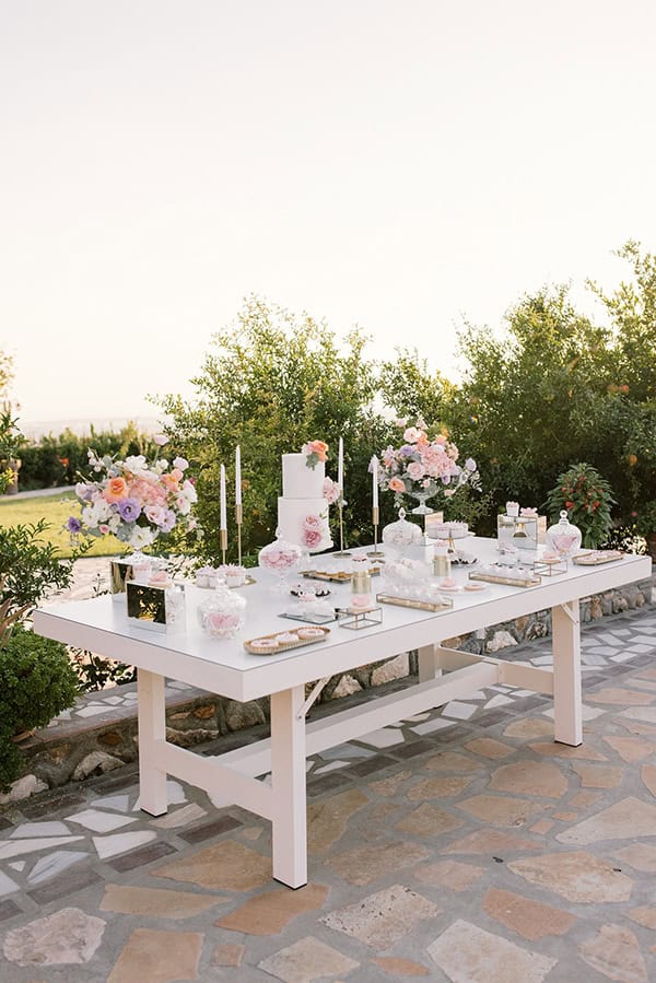 Διακόσμηση candy table με πληθώρα λουλουδιών μέσα σε clear βάζα