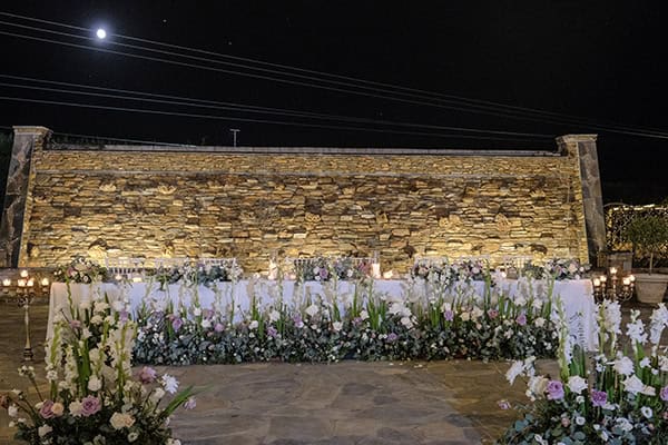 Διακόσμηση γαμήλιου τραπεζιού πλημμυρισμένο από όμορφα τριαντάφυλλα και λευκό λυσίανθο