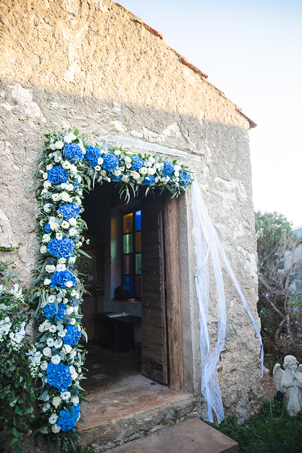 Όμορφος στολισμός εισόδου εκκλησίας με γιρλάντα λουλουδιών από μπλε ορτανσίες