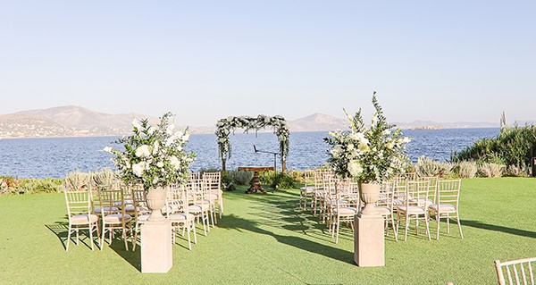 Ρομαντική διακόσμηση τελετής εξωτερικού χώρου με αμφορείς και λουλουδένια αψίδα