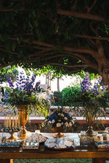 Elegant στολισμός dessert table με πλούσιο ανθοστολισμό μέσα σε χρυσά βάζα