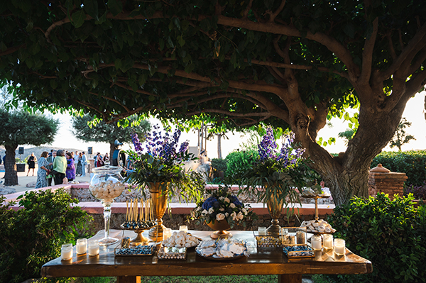Elegant στολισμός dessert table με πλούσιο ανθοστολισμό μέσα σε χρυσά βάζα