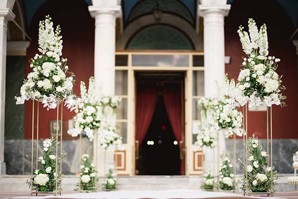 Όμορφος στολισμός εισόδου εκκλησίας με λευκά δελφίνιουμ και ορτανσίες σε gold stands Όμορφος στολισμός εισόδου εκκλησίας με λευκά δελφίνιουμ και ορτανσίες σε gold stands