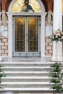 Όμορφος στολισμός εισόδου εκκλησίας με χρυσά stand και λευκά κεριά