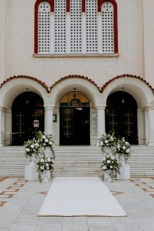 All white διακόσμηση εισόδου εκκλησίας με ρομαντικές ανθοσυνθέσεις