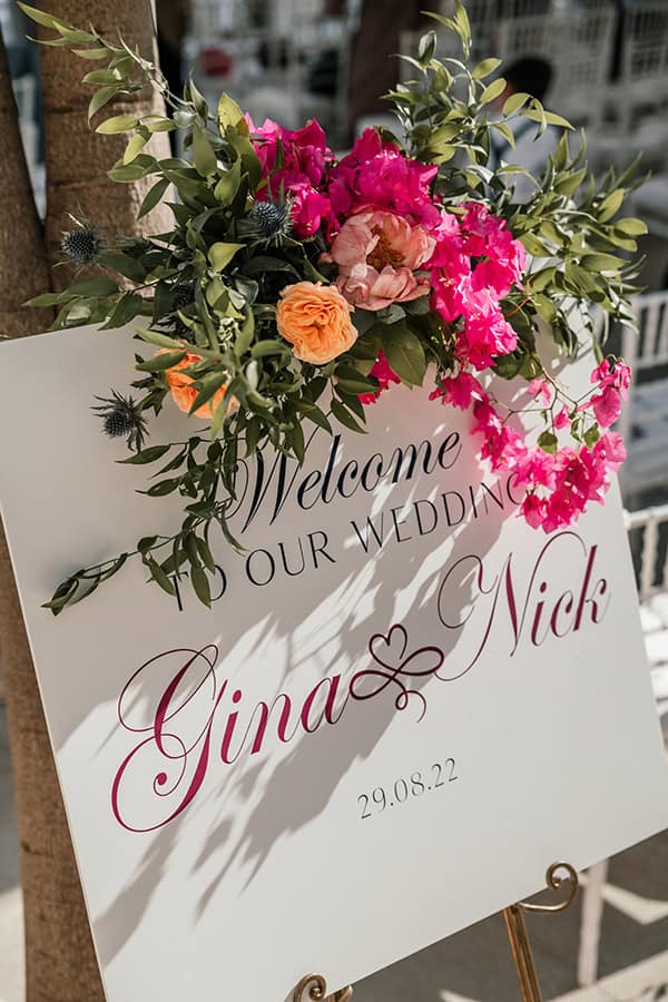 Πινακίδα καλωσορίσματος με διακόσμηση απο φούξια βουκαμβίλιες και τριαντάφυλλα
