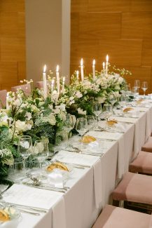 Ρομαντικός στολισμός τραπεζιών δεξίωσης με πλούσια πρασινάδα και λευκά κεριά